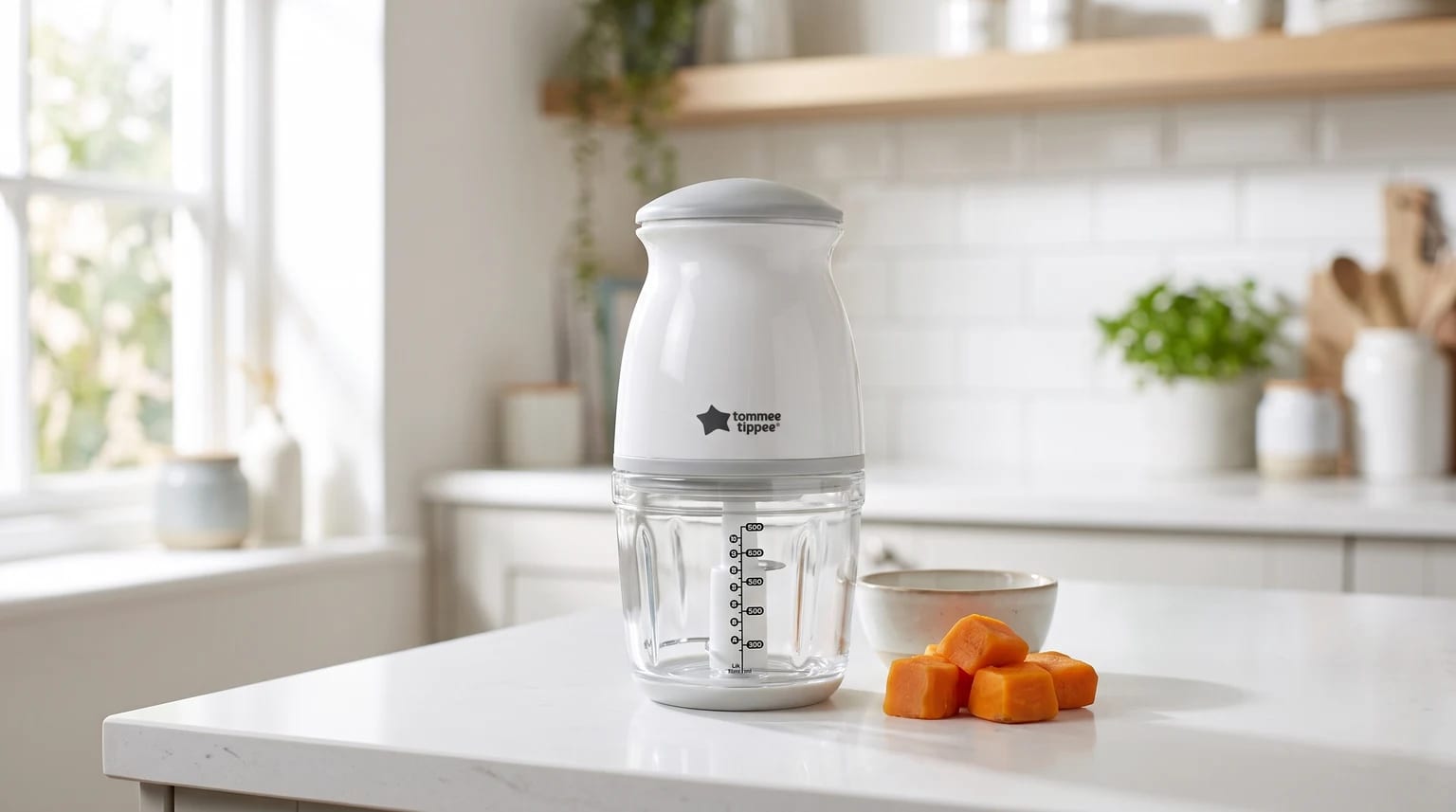 The Tommee Tippee baby food blender on a bright kitchen worktop, with cubes of cooked sweet potato and a small bowl nearby.