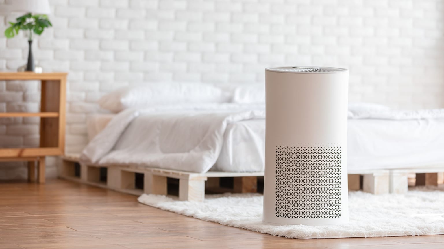 An air purifier working next to a bed.