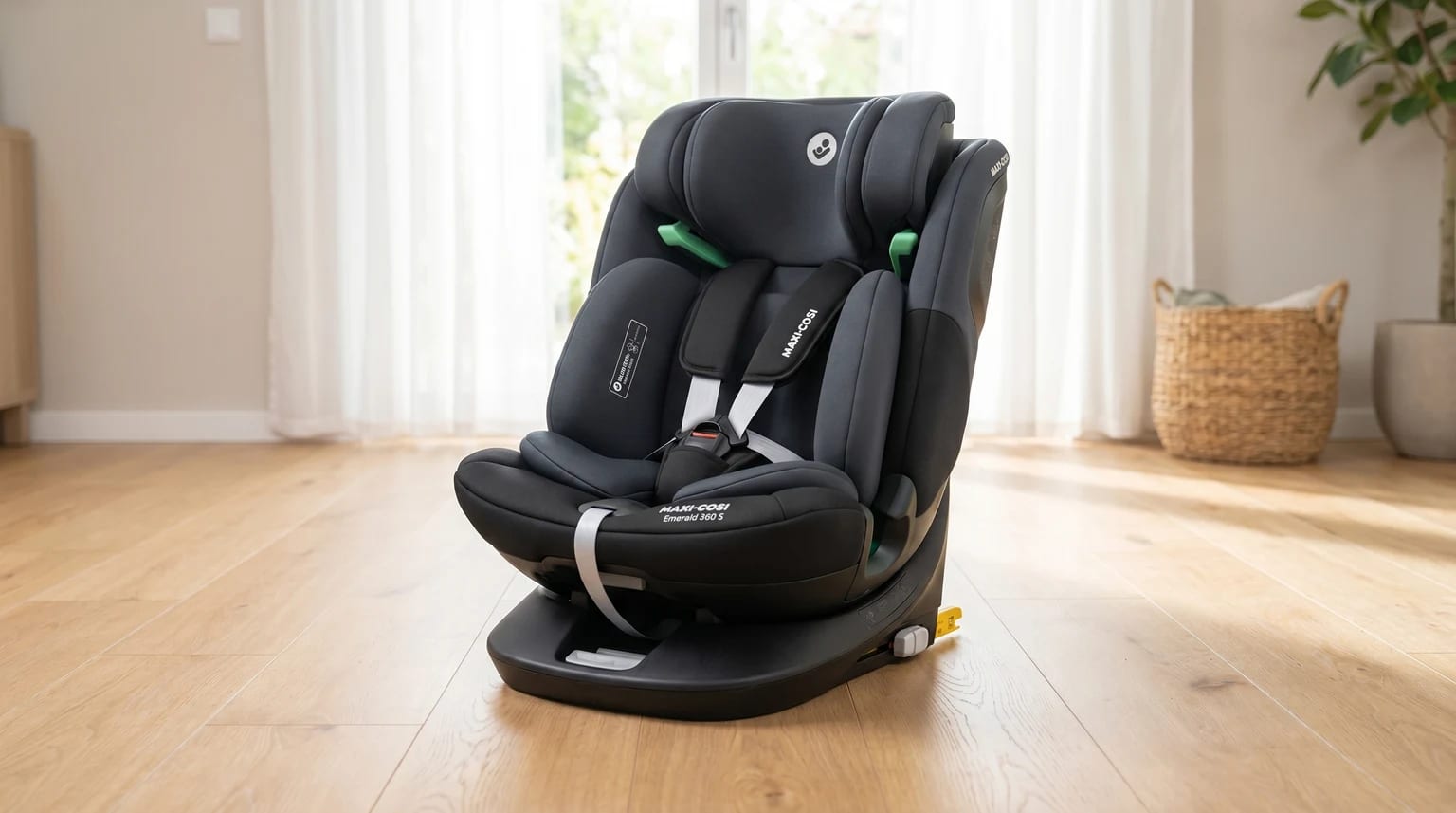 The dark grey Maxi-Cosi Emerald 360 S car seat, placed on a light wooden floor in a sunlit room.