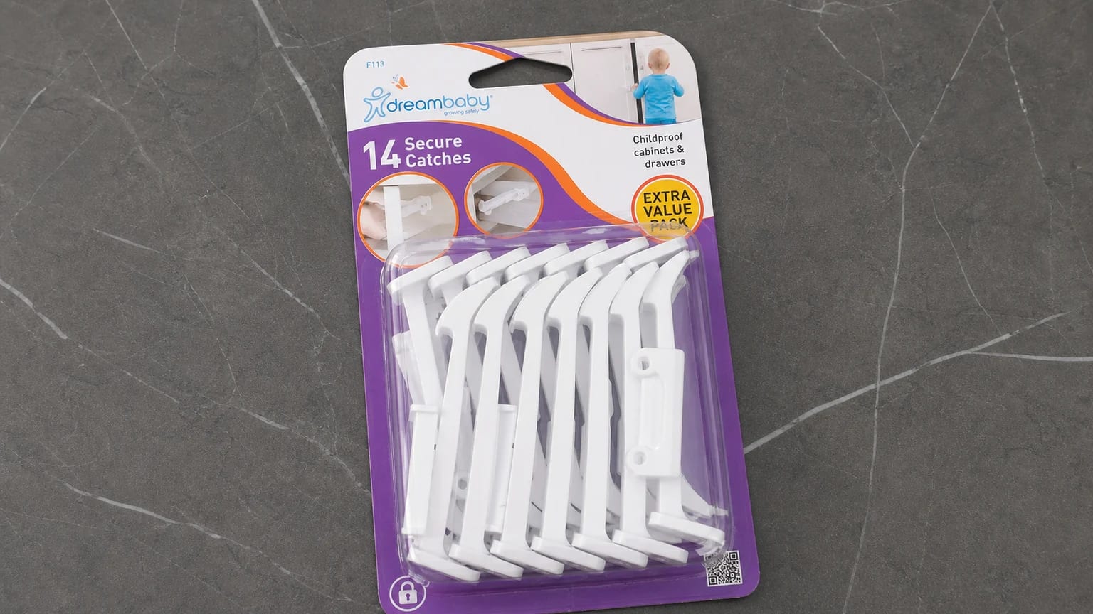 A Dreambaby pack of white screw-fit secure catches in purple blister packaging on a grey worktop.
