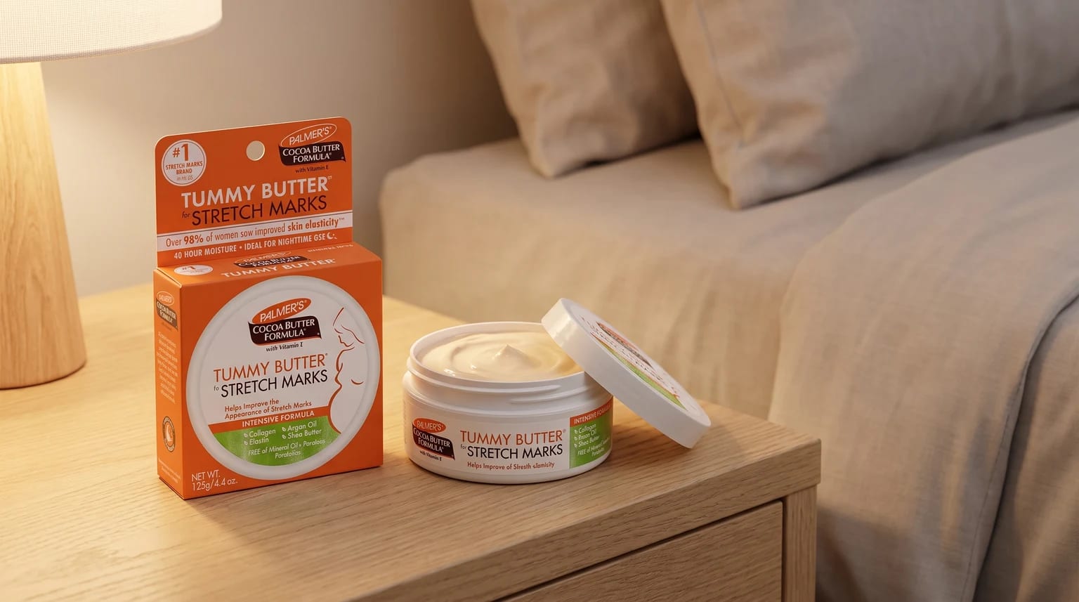 An open tub of Palmer's Tummy Butter for stretch marks sits on a wooden bedside table next to its orange box in a calm bedroom.
