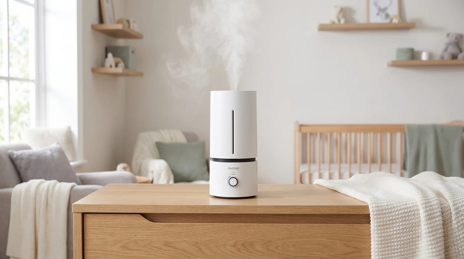 A white cool mist humidifier sits on a wooden chest of drawers in a nursery, releasing a gentle plume of vapour with a cot in the background.