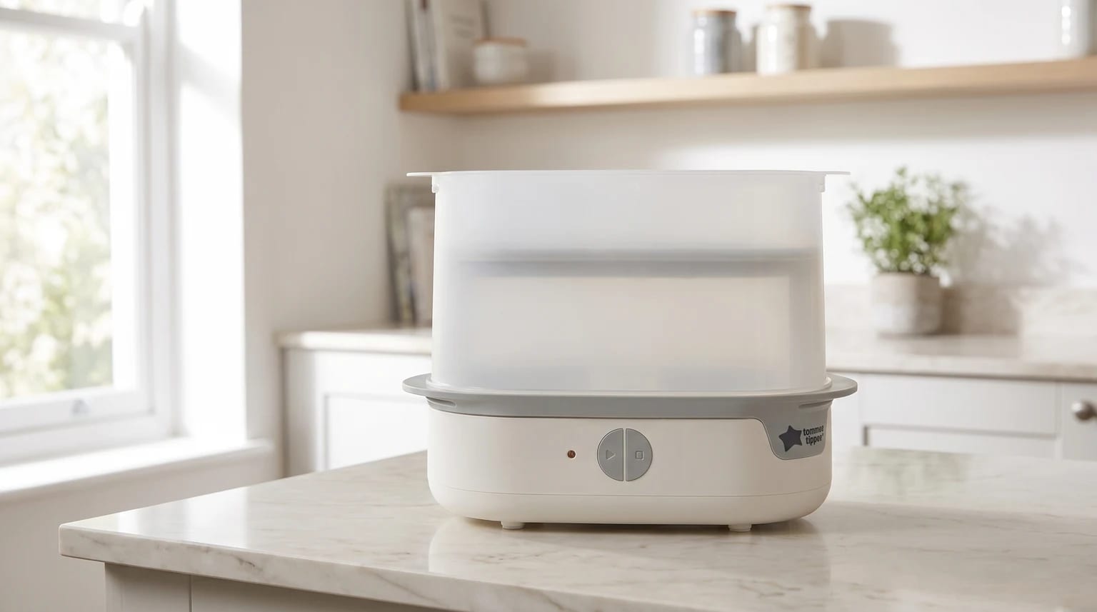A white Tommee Tippee electric steam steriliser sitting on a marble-effect kitchen worktop in a bright, modern kitchen.