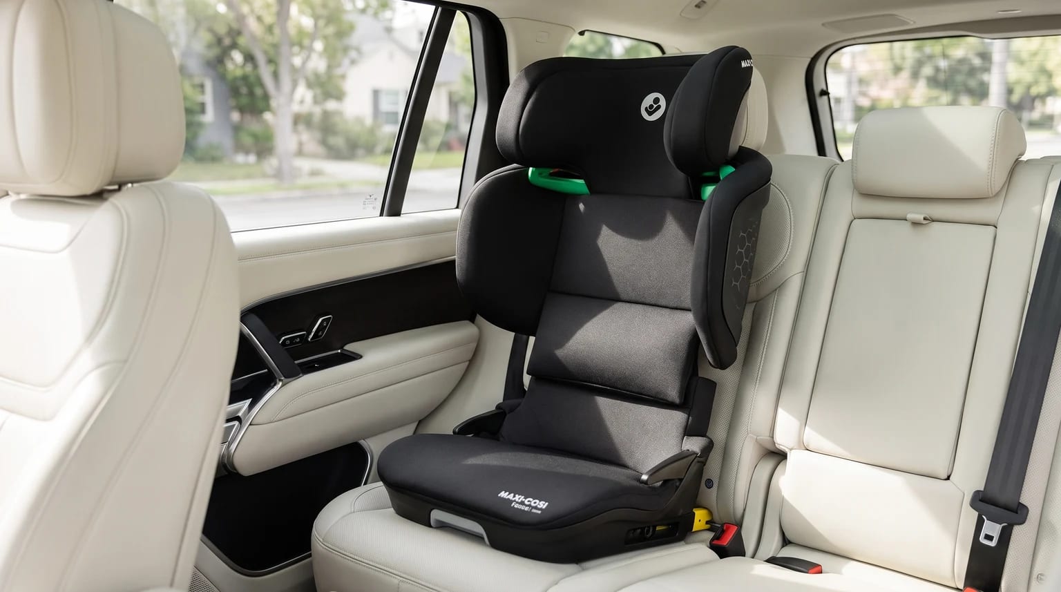 A black Maxi-Cosi high-back booster seat fitted onto the cream leather back seat of a modern car.